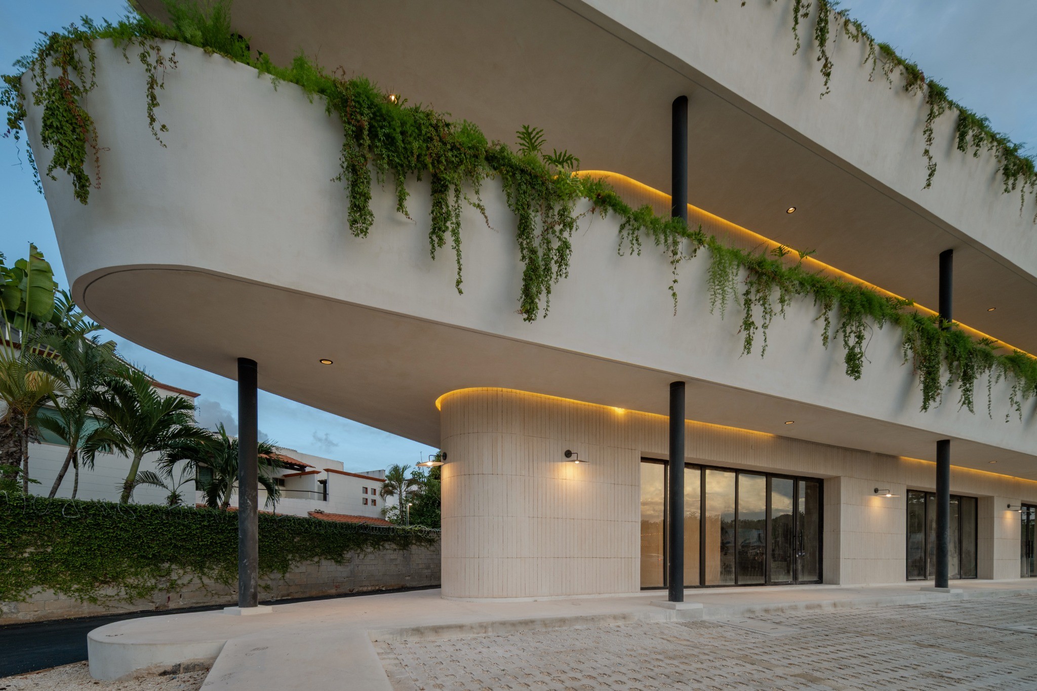 Fachada de Triángulo Huayacán con vegetación e iluminación cálida